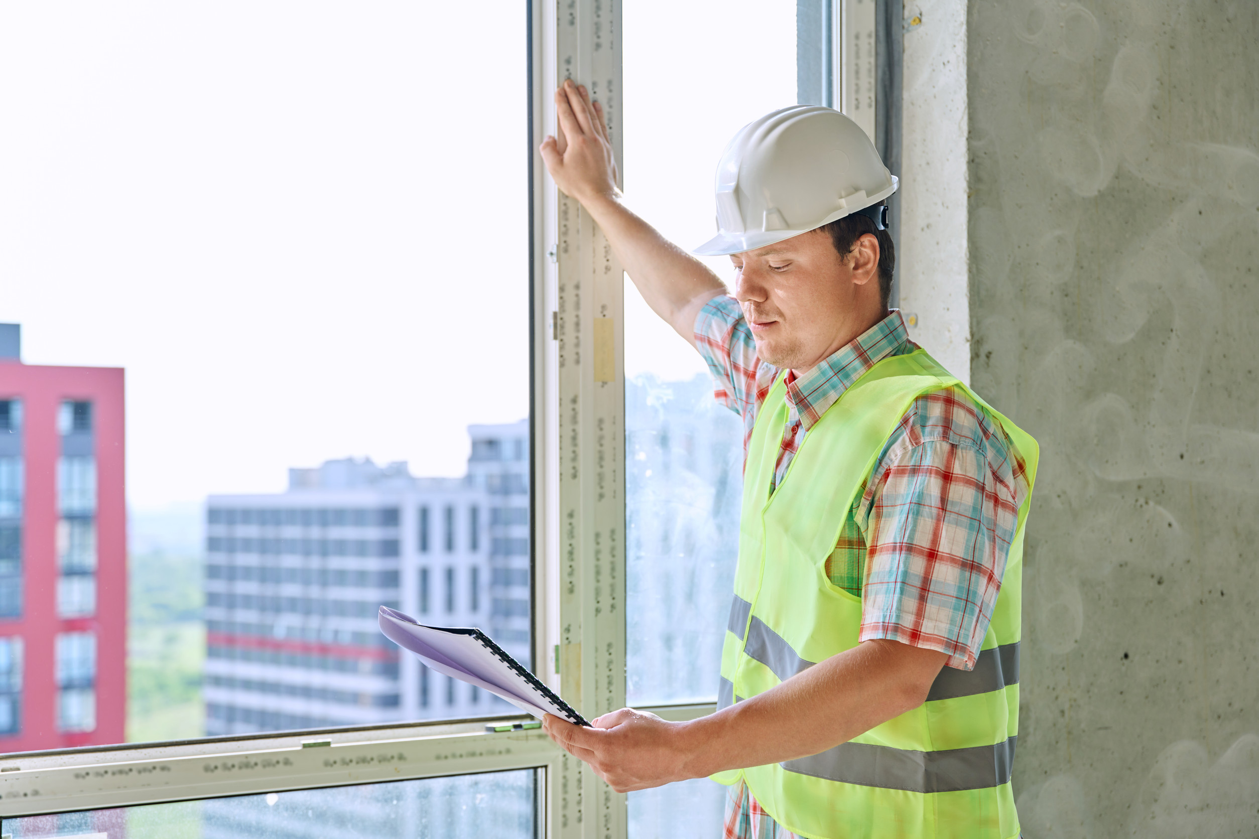 Portrait of male industrial worker in vest helmet with engineering documents